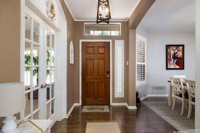 foyer entrance with arched walkways, dark wood finished floors, and baseboards