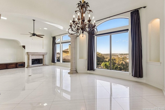 unfurnished living room featuring ornate columns, a premium fireplace, arched walkways, ceiling fan, and marble finish floor