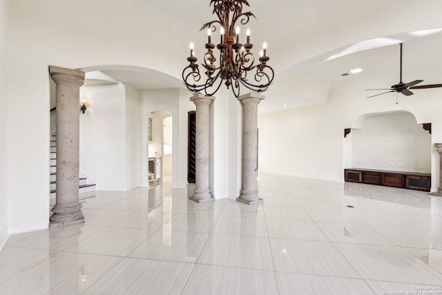 empty room featuring decorative columns, arched walkways, ceiling fan, and stairs