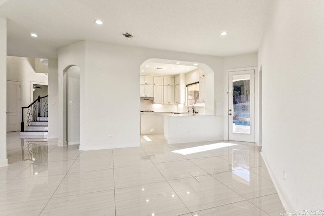 unfurnished living room with visible vents, recessed lighting, baseboards, and arched walkways