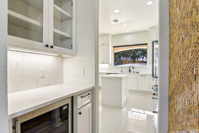 interior space featuring beverage cooler, a sink, recessed lighting, light tile patterned floors, and decorative backsplash