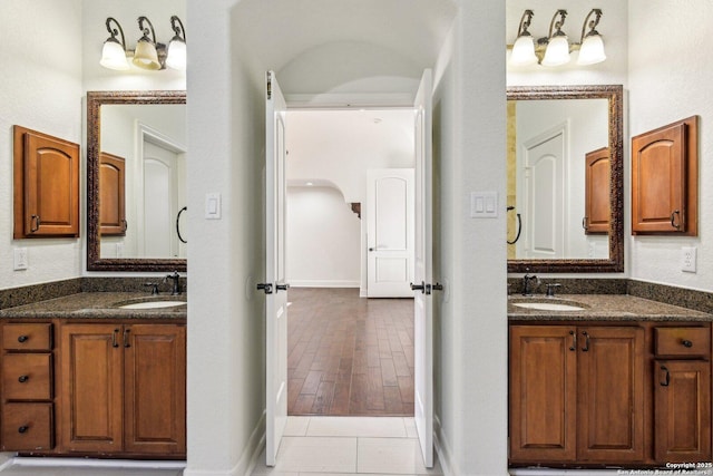 bathroom featuring tile patterned floors, two vanities, and a sink