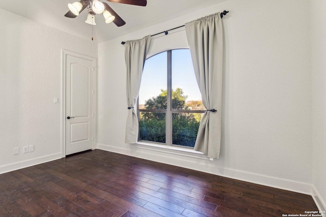 empty room with baseboards, a ceiling fan, and dark wood-style flooring