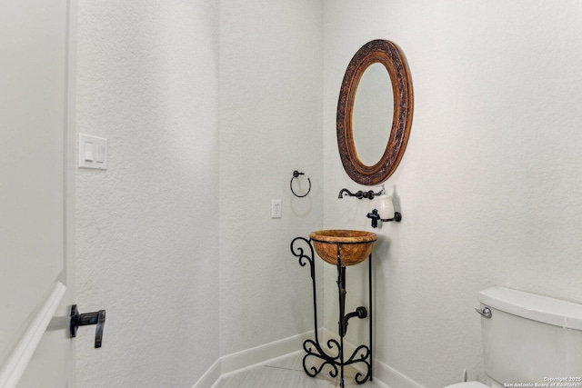 bathroom featuring toilet and baseboards