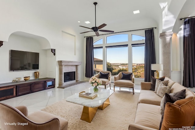 living room featuring light tile patterned floors, a fireplace, decorative columns, and ceiling fan