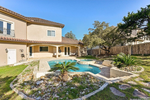 view of pool featuring french doors, a patio area, a pool with connected hot tub, and fence