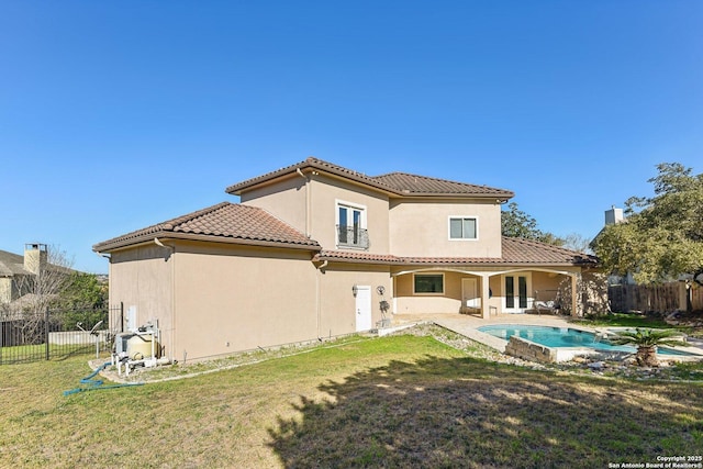 rear view of house featuring a fenced in pool, a yard, a fenced backyard, stucco siding, and a tiled roof