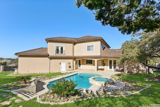 rear view of property featuring stucco siding, french doors, a tiled roof, a patio area, and a lawn