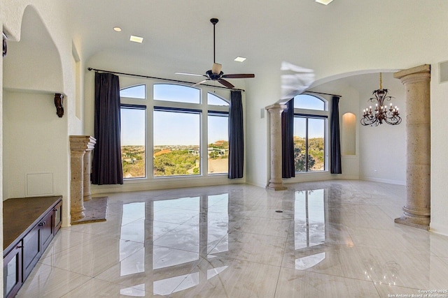 unfurnished living room with plenty of natural light, arched walkways, marble finish floor, and ornate columns