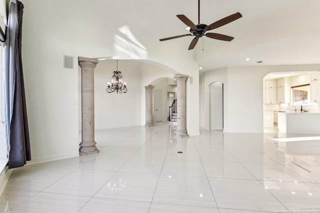 empty room with visible vents, ornate columns, arched walkways, a ceiling fan, and a sink