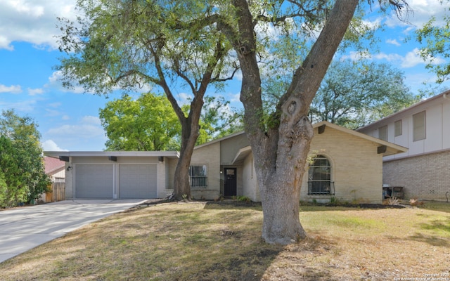 mid-century home with brick siding, an attached garage, concrete driveway, and a front yard