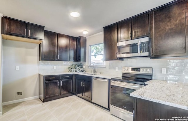 kitchen with a sink, appliances with stainless steel finishes, decorative backsplash, light stone countertops, and dark brown cabinets