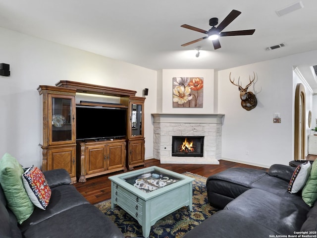 living area featuring dark wood finished floors, visible vents, a fireplace, and a ceiling fan