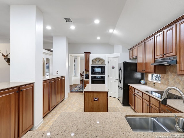 kitchen with a kitchen island, a sink, black appliances, under cabinet range hood, and backsplash