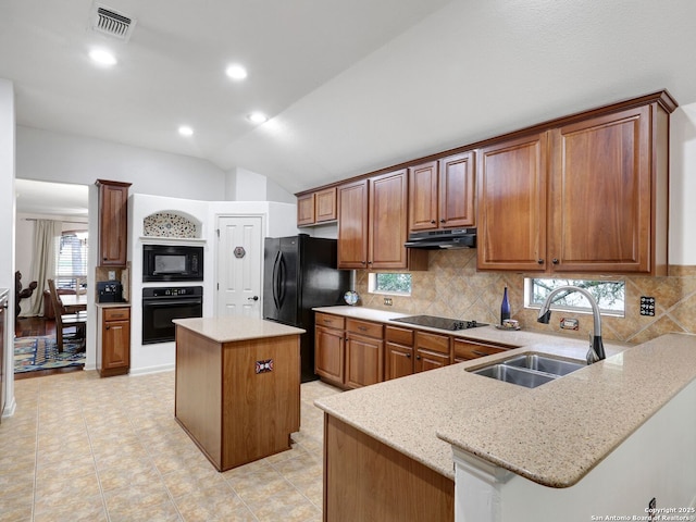 kitchen featuring visible vents, black appliances, a sink, under cabinet range hood, and light stone countertops