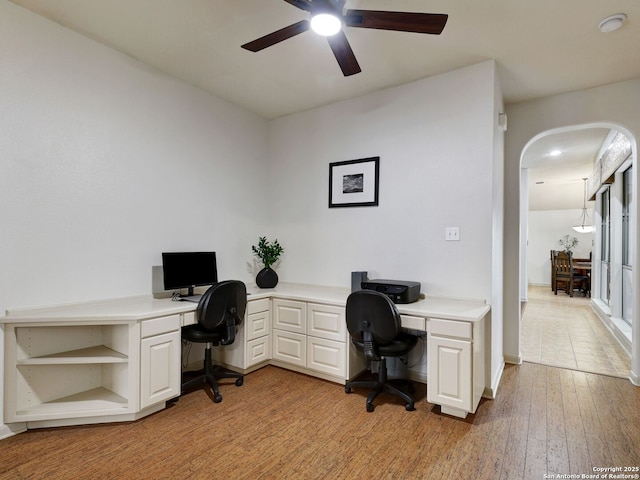 home office featuring arched walkways, light wood finished floors, and ceiling fan