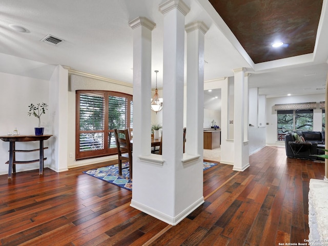 hallway featuring visible vents, baseboards, hardwood / wood-style floors, and ornate columns