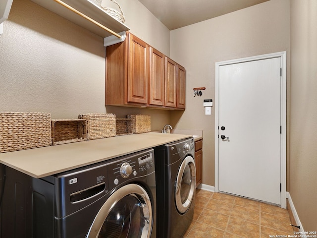 laundry area with a sink, washing machine and dryer, cabinet space, light tile patterned floors, and baseboards