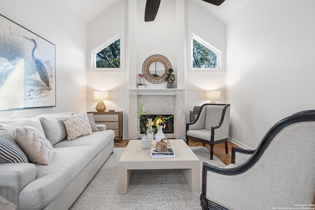 living room featuring baseboards, lofted ceiling, a healthy amount of sunlight, and a tile fireplace