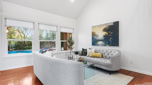 living area featuring high vaulted ceiling, baseboards, and wood finished floors