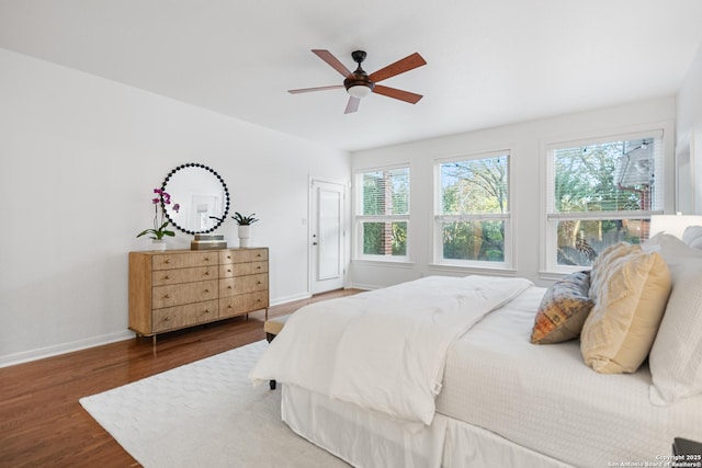 bedroom with ceiling fan, baseboards, and wood finished floors