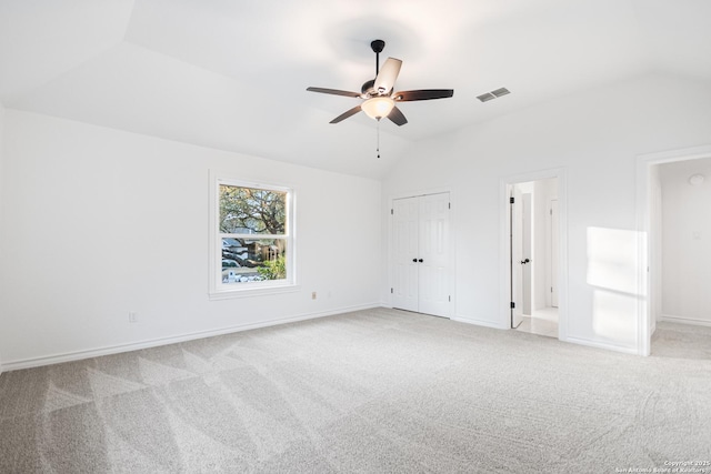 unfurnished room with lofted ceiling, light colored carpet, visible vents, and baseboards