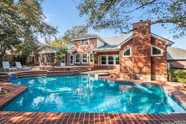 view of pool featuring a patio area, a pool with connected hot tub, fence, and a sunroom