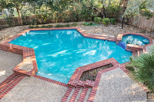 view of swimming pool featuring a fenced backyard and a pool with connected hot tub