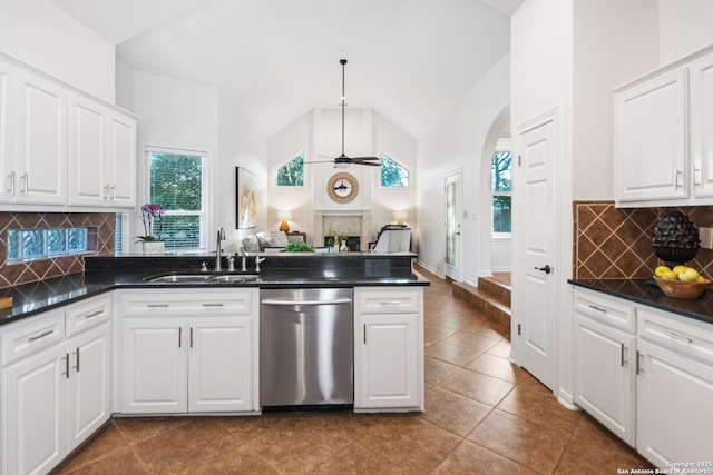 kitchen with arched walkways, ceiling fan, a sink, dishwasher, and dark countertops