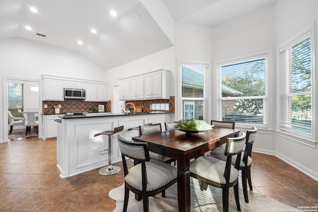 tiled dining room featuring visible vents, baseboards, recessed lighting, high vaulted ceiling, and a sink