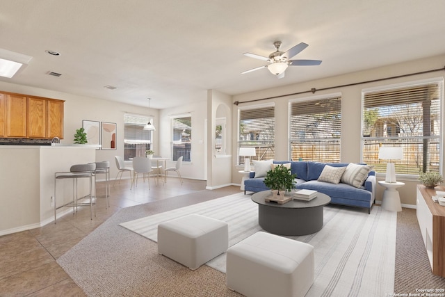 living area featuring light tile patterned flooring, baseboards, visible vents, and ceiling fan