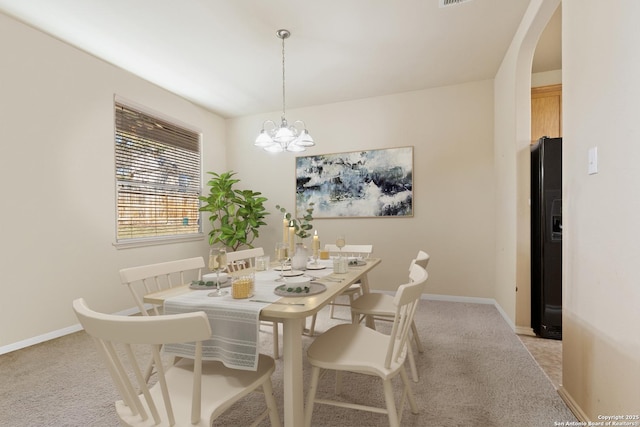 dining area featuring baseboards, light colored carpet, a chandelier, and arched walkways