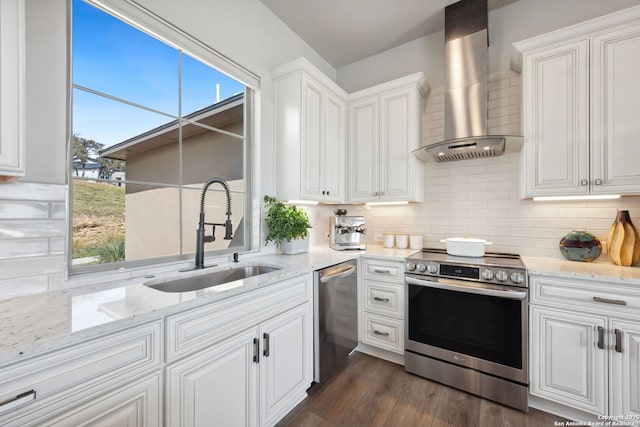 kitchen with a sink, decorative backsplash, stainless steel appliances, white cabinetry, and wall chimney range hood