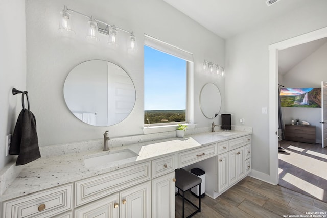 full bath with double vanity, wood finished floors, baseboards, and a sink