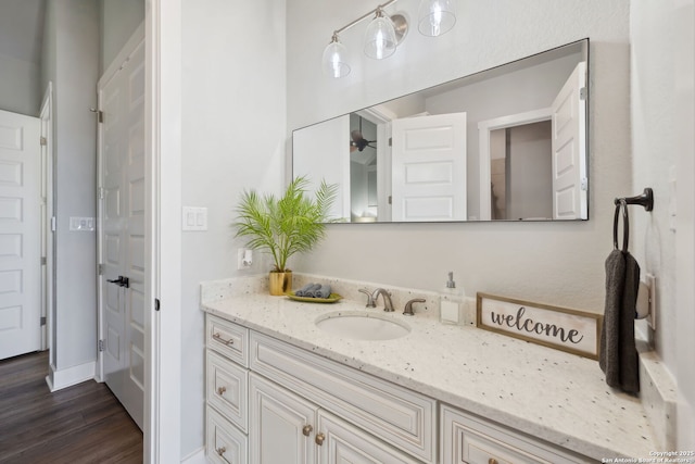 bathroom with vanity, wood finished floors, baseboards, and ceiling fan