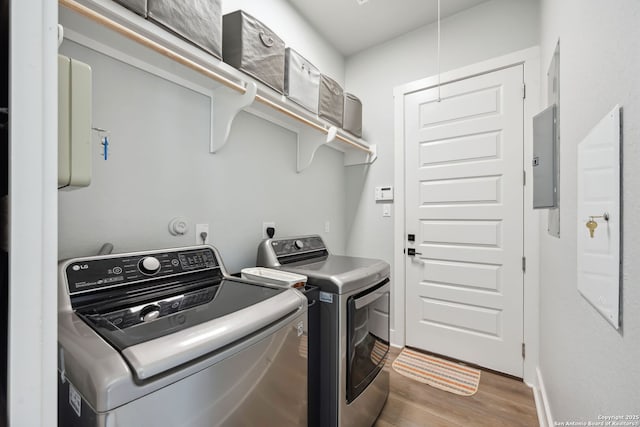 clothes washing area with baseboards, wood finished floors, laundry area, and washing machine and clothes dryer