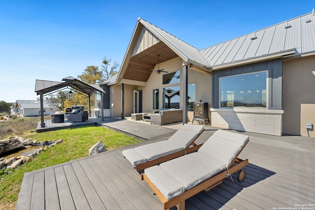 wooden terrace with a gazebo, an outdoor hangout area, and a ceiling fan