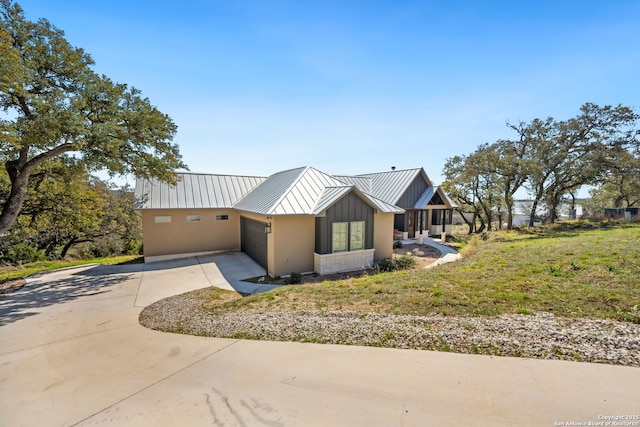 view of front of home with a standing seam roof, concrete driveway, a garage, and metal roof