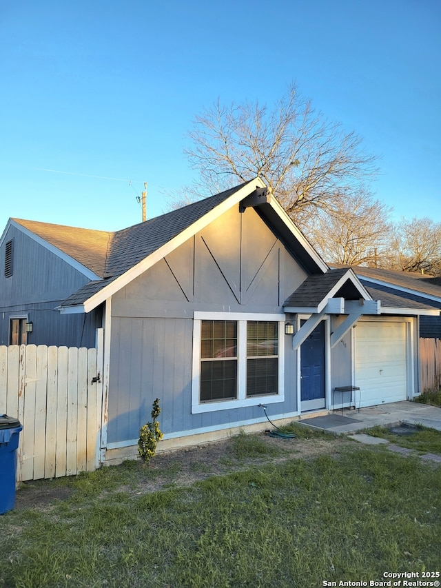 view of front of home featuring a garage, fence, a shingled roof, and a front lawn