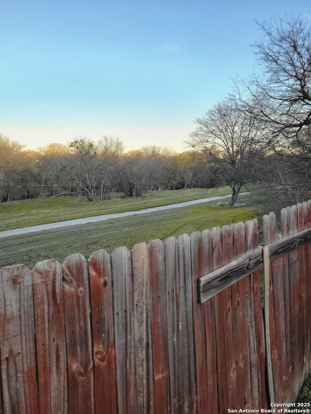 yard at dusk featuring fence and a water view