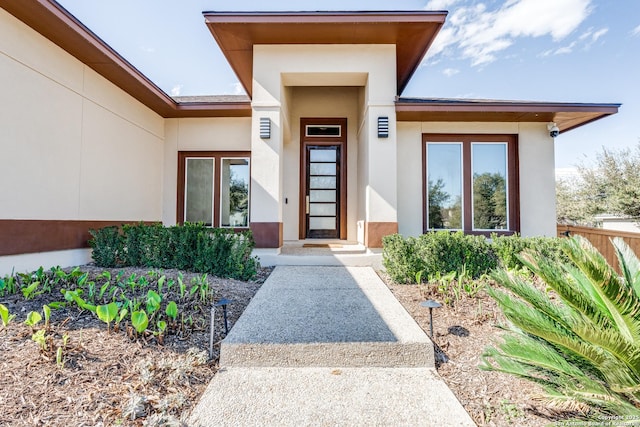 property entrance featuring stucco siding and fence