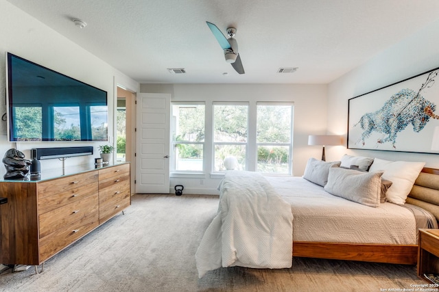 bedroom with a ceiling fan, visible vents, and light carpet