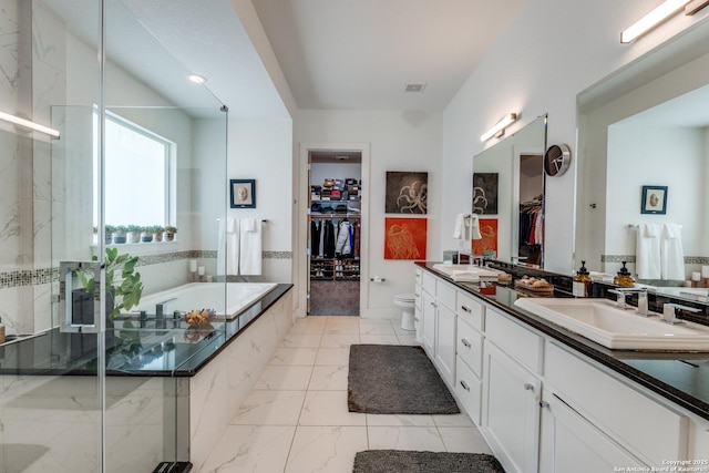 bathroom featuring double vanity, marble finish floor, a stall shower, and a sink