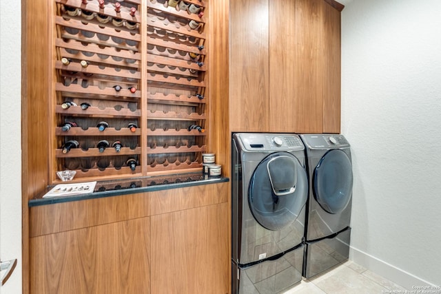 clothes washing area featuring washing machine and clothes dryer, baseboards, a textured wall, tile patterned floors, and cabinet space