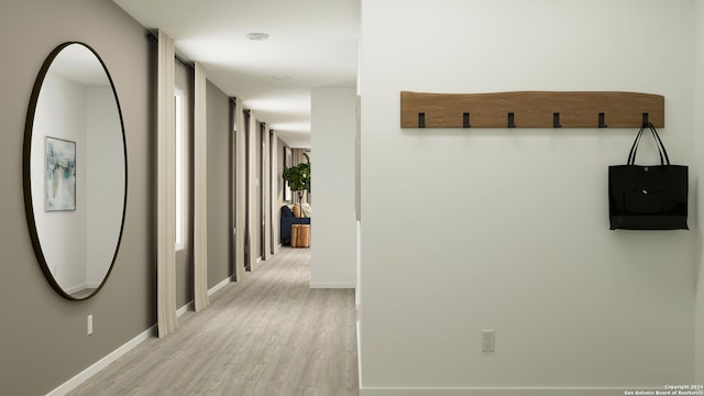 hall featuring light wood-type flooring and baseboards