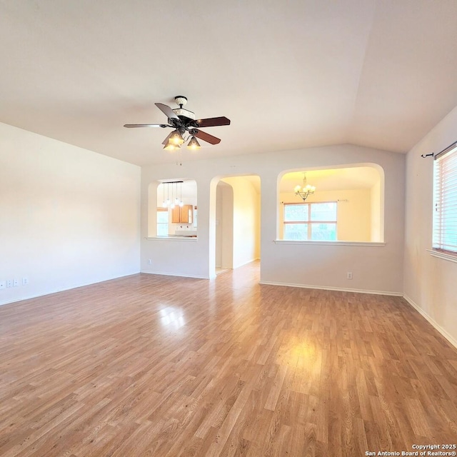 unfurnished living room featuring light wood-type flooring, arched walkways, vaulted ceiling, and ceiling fan with notable chandelier