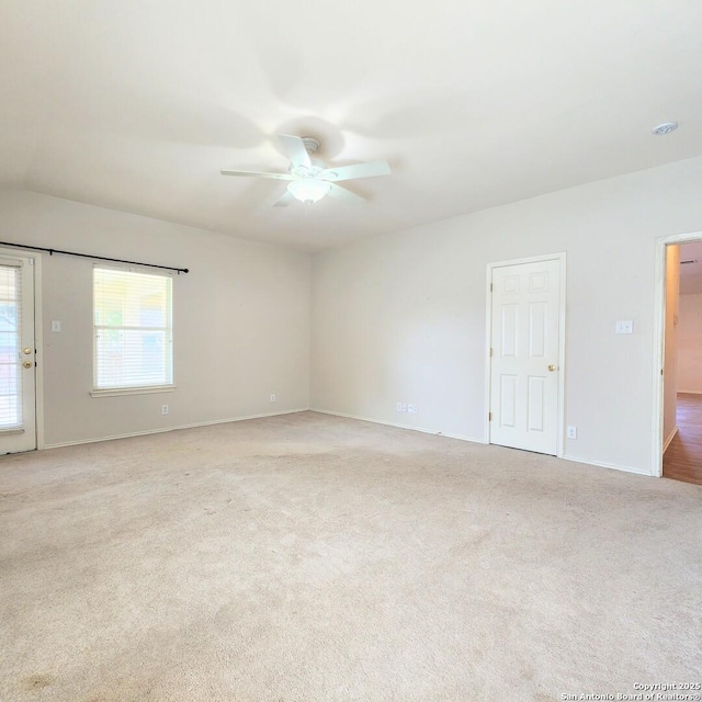 empty room with light colored carpet and a ceiling fan