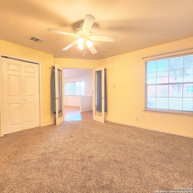 unfurnished bedroom with a ceiling fan, visible vents, french doors, a closet, and carpet flooring