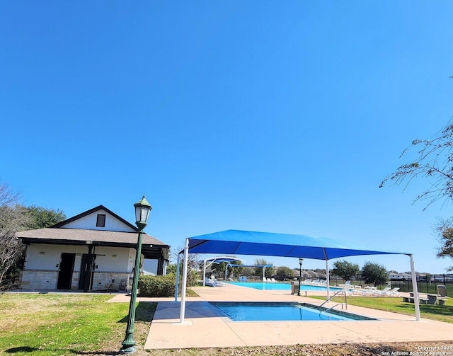 view of property's community with a swimming pool, a lawn, and fence