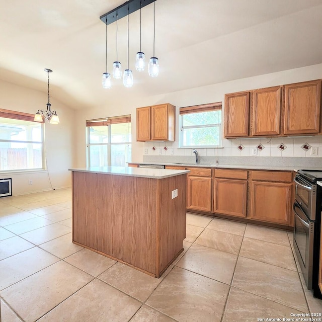 kitchen featuring a kitchen island, light countertops, lofted ceiling, brown cabinetry, and stainless steel appliances